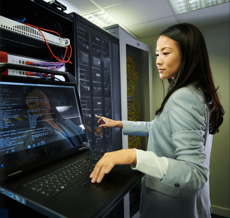 Woman working on a computer in a server room.