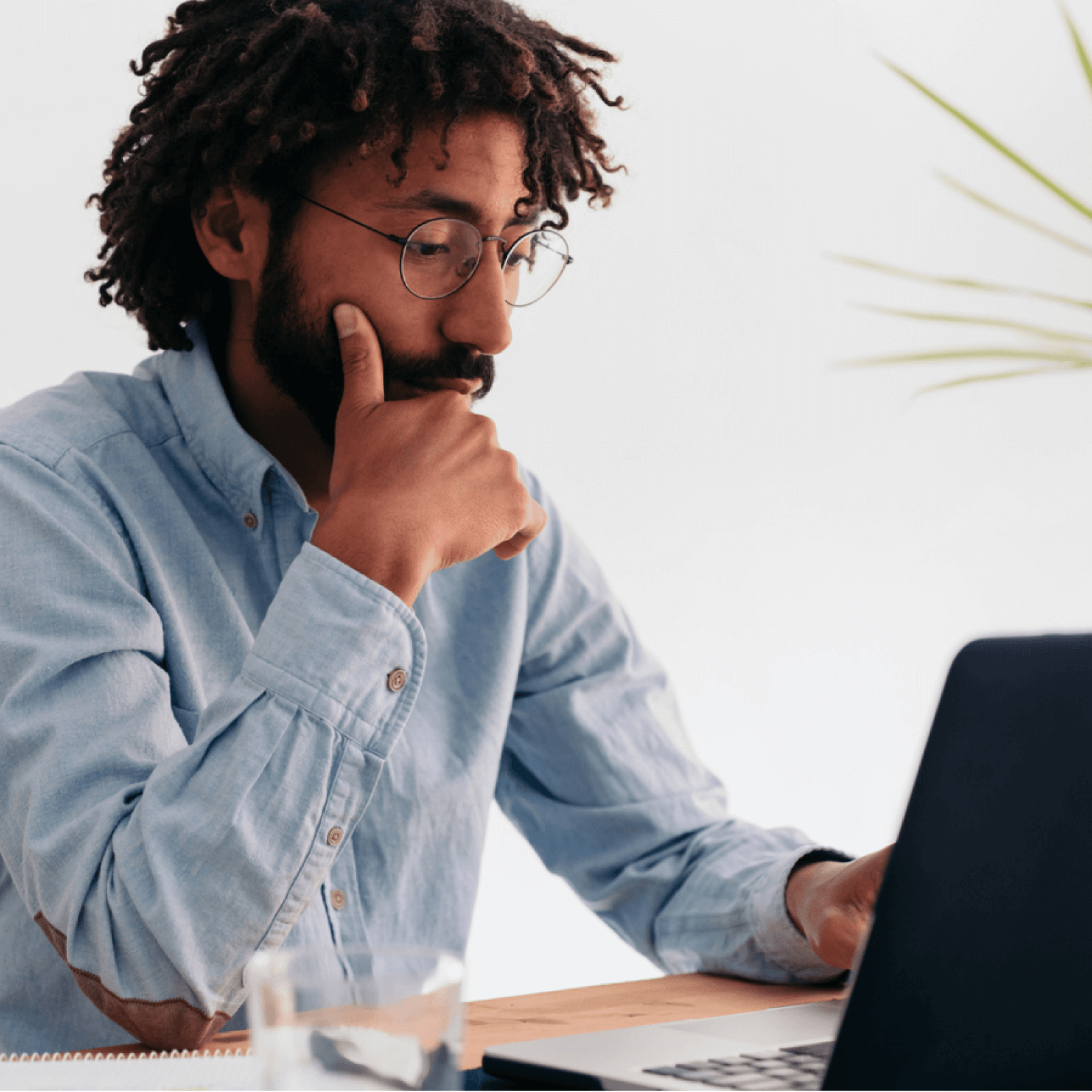 Man in glasses works at laptop.